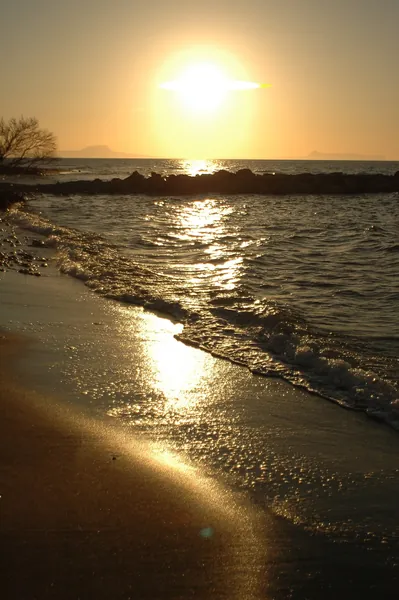 Image d'un coucher de soleil en train de se coucher sur la mer et une plage de sable fin