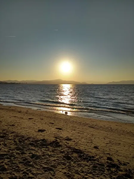 Image d'un coucher de soleil sur une mer calme et d'une plage de sable